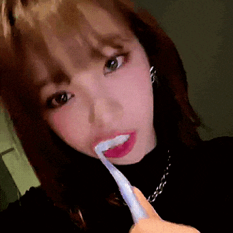 a woman is brushing her teeth with a white toothbrush
