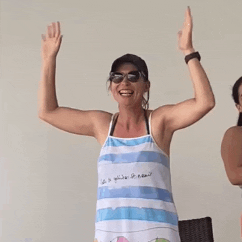 a woman wearing a blue and white striped apron has her arms in the air .