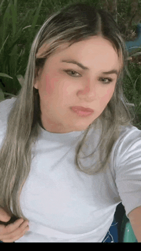 a woman in a white shirt is taking a selfie with her hand on her hip