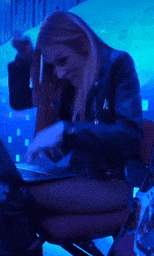 a woman in a leather jacket is sitting in front of a laptop computer .