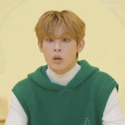 a young man wearing a green vest and a white shirt is making a funny face