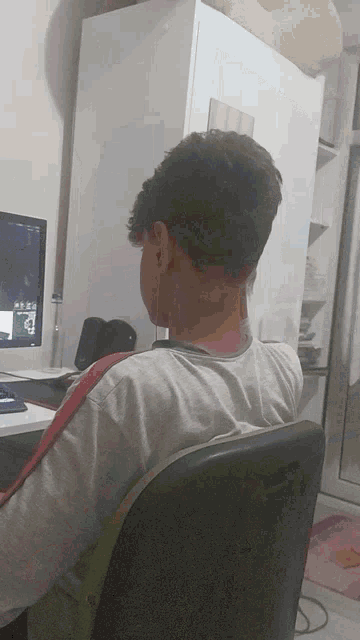 a man sits in front of a computer with the letter b on the screen