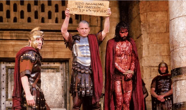 a man in armor holds up a sign that says jesus nazarenas rex inaeorum
