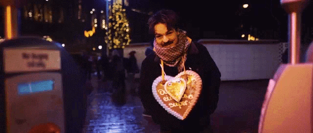 a person holding a heart shaped cookie that says ' a ' on the front