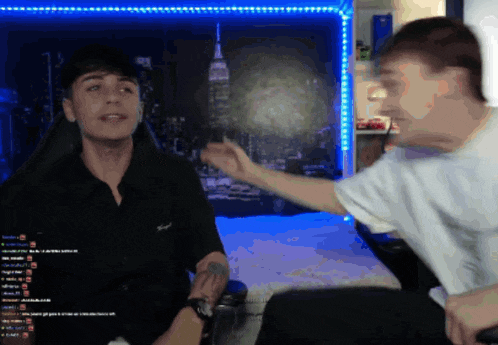 a man in a black shirt is talking to another man in a white shirt in front of a picture of the empire state building