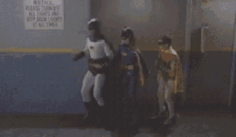 batman and batgirl are standing next to each other in front of a sign that says " keep door locked at all times "