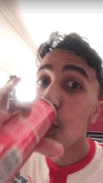 a young man is drinking from a can with the word coca cola on it
