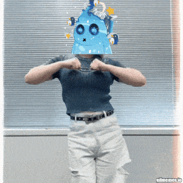 a woman with a blue monster mask on her head is standing in front of a window