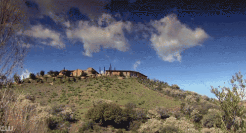 a house sits on top of a hill with a cw logo in the corner