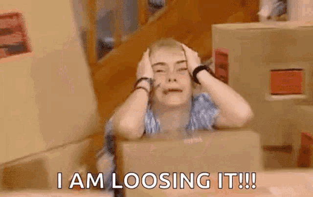 a woman is sitting in a box with her hands on her head and the words `` i am loosing it '' .
