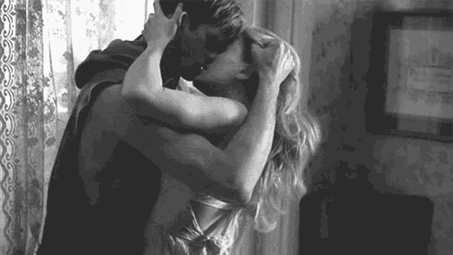 a man and a woman are hugging and kissing in a black and white photo .