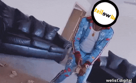a man in a blue suit is holding a bag of money in front of a couch