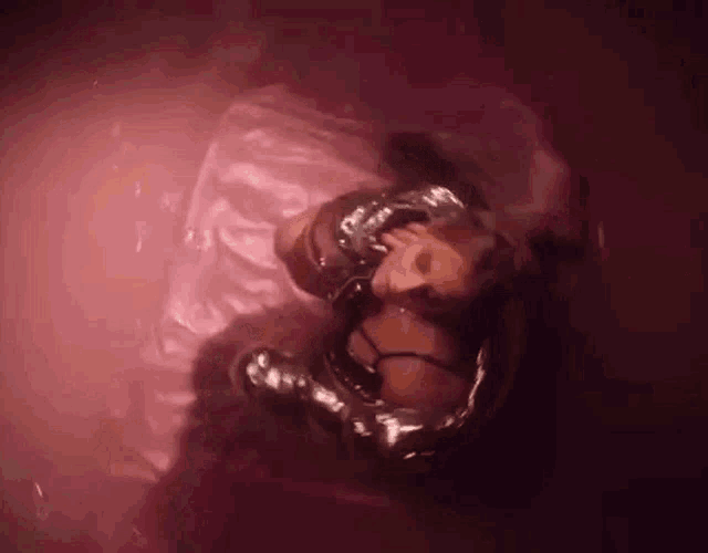 a woman is laying on a pink sheet in a bathtub .