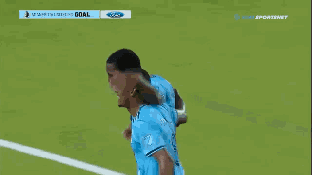 two soccer players are celebrating a goal on the field