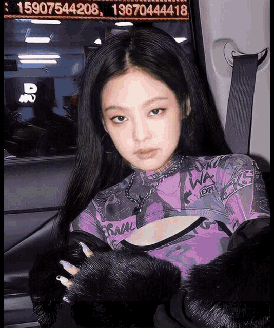 a woman wearing a purple top and black fur sleeves is sitting in a car