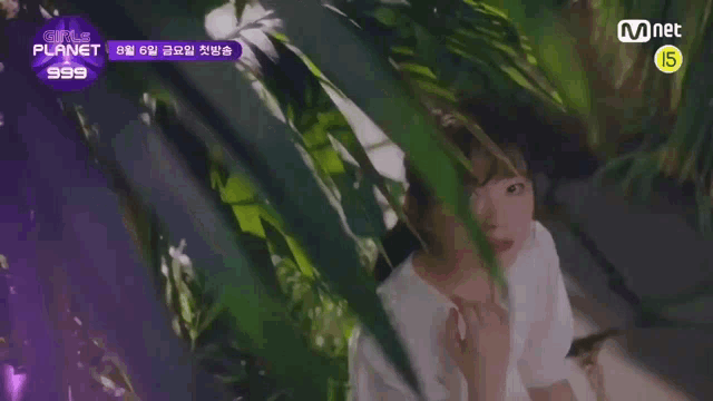 a girl in a white shirt is standing in a jungle behind a tree .