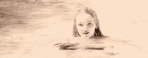 a young woman is swimming in a pool and looking at the camera .