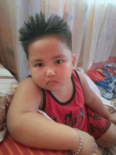 a little boy wearing a red tank top that says ' ninja ' on it
