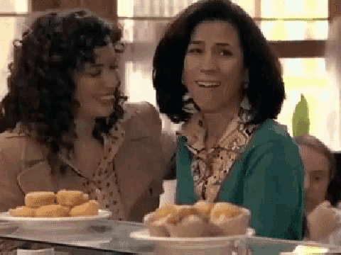 two women are sitting at a table with a plate of food .
