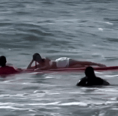 a woman is laying on a surfboard in the water
