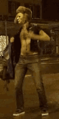 a shirtless man with a mask on his face is dancing in the street