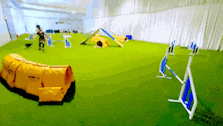 a blurry picture of a dog agility course with a yellow bag in the foreground