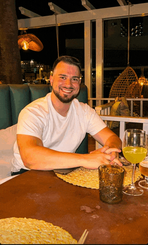 a man is sitting at a table with a glass of wine