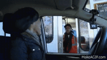 a woman sitting in a car talking to a man in an orange vest
