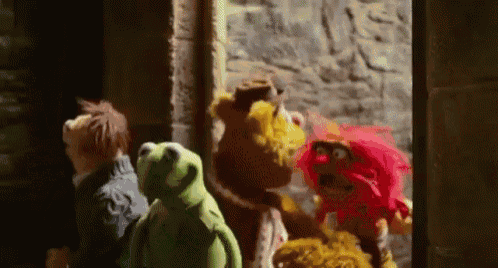 a group of stuffed animals are standing next to each other in front of a stone wall .
