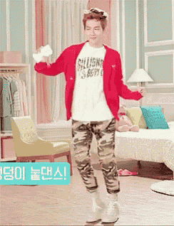 a man wearing a red cardigan and a billionaire shirt is dancing in a room