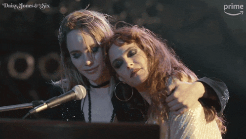 two women hugging in front of a microphone with the words daisy jones & six on the bottom left
