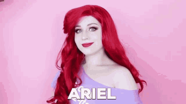 a woman with red hair is wearing a wig and a purple shirt and is dressed as ariel from the little mermaid .