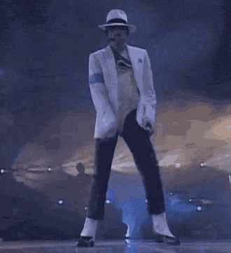 a man in a white suit and hat is dancing on stage