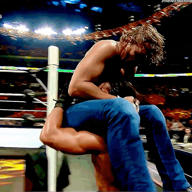 a wrestler is carrying another wrestler in a wrestling ring with the hashtag #thenextround