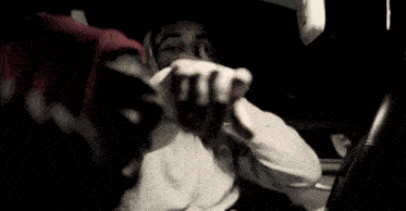 a man is eating a hamburger in a car while wearing a head scarf .