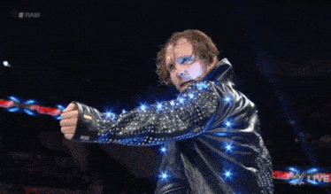 a wrestler is holding a red rope while wearing a black jacket with rhinestones on the sleeves