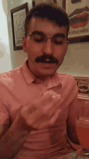 a man with glasses and a mustache is eating a piece of food