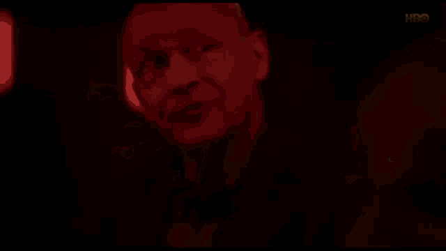 a bald man is standing in the dark in a red light .