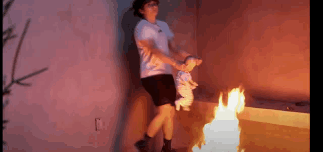 a woman is holding a baby in front of a burning fire .