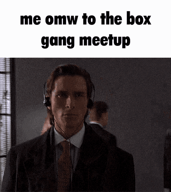 a man in a suit and tie wearing headphones says me omw to the box gang meetup