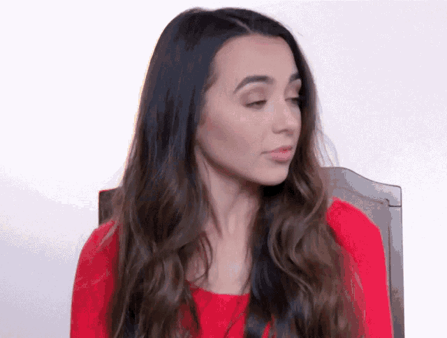 a woman with long dark hair is wearing a red shirt