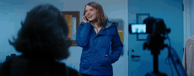 a woman wearing a blue jacket is talking on a cell phone