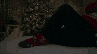a woman is laying on a bed with a christmas tree in the background .