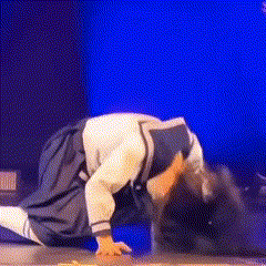 a girl is kneeling down on the floor with her hands up in the air
