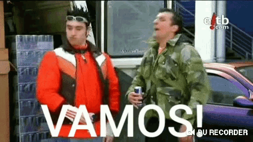 two men are standing in front of a purple car with the word vamos on the screen