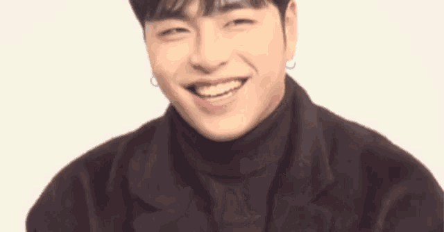 a young man wearing a turtleneck and a jacket is smiling and looking at the camera .