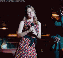 a woman singing into a microphone while standing next to a man in a suit