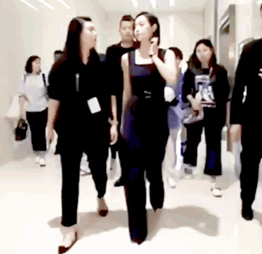 a group of people are walking down a hallway with a woman wearing a name tag that says ' a '
