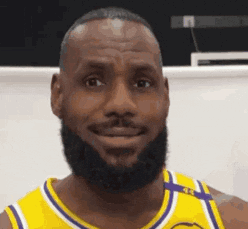lebron james is wearing a yellow and purple jersey and smiling .