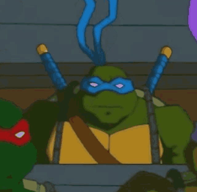 a group of teenage mutant ninja turtles are sitting around a table and one of them is covering his eyes with his hands